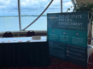 A banner sits beside the exhibit table for Wong Fleming with large text that reads "Out-of-State Tax Lien Enforcement"